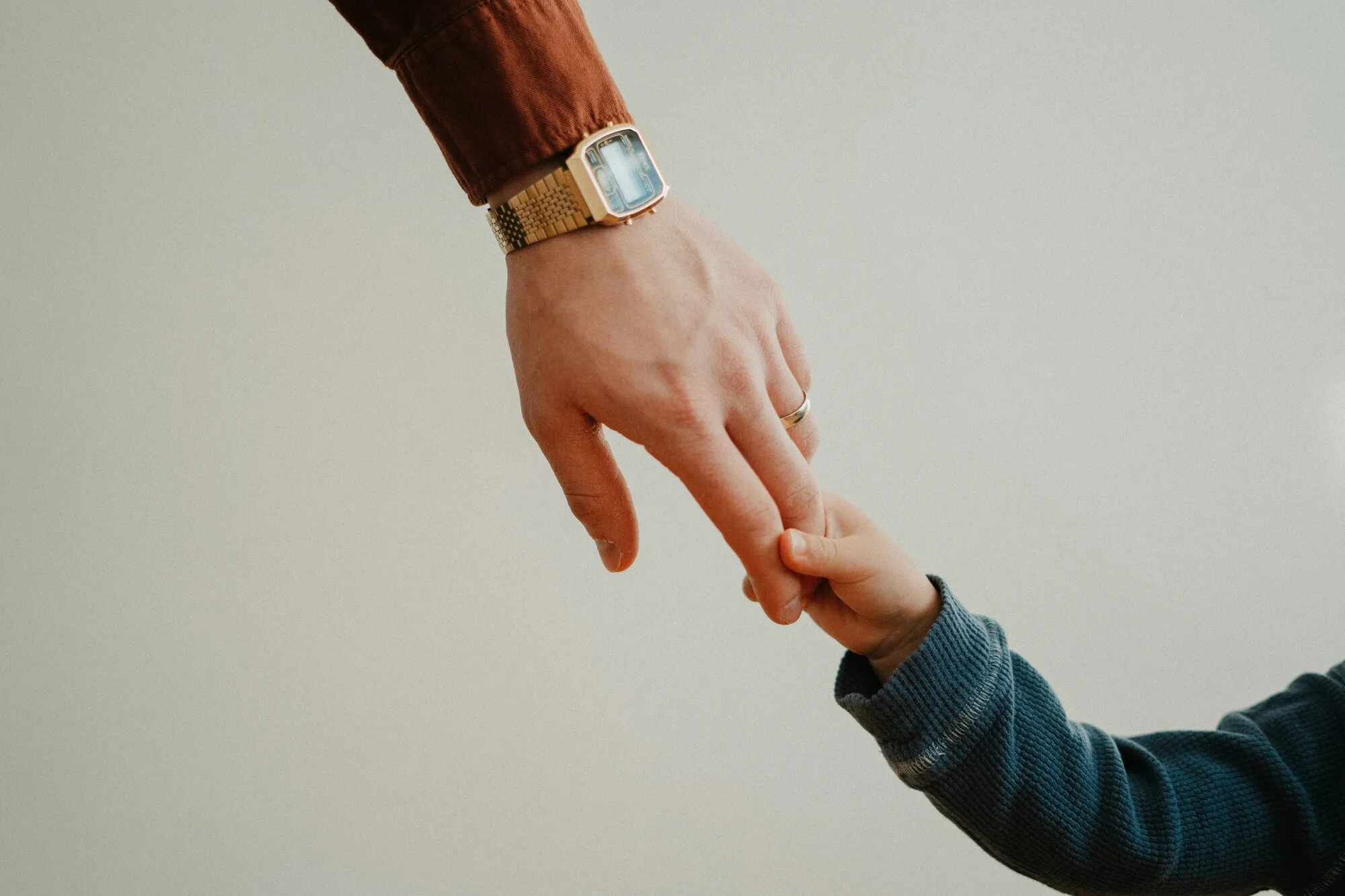 An adult holding a young child's hand